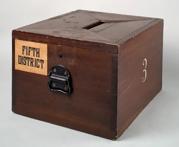 An old wooden ballot box with a slot in the lid