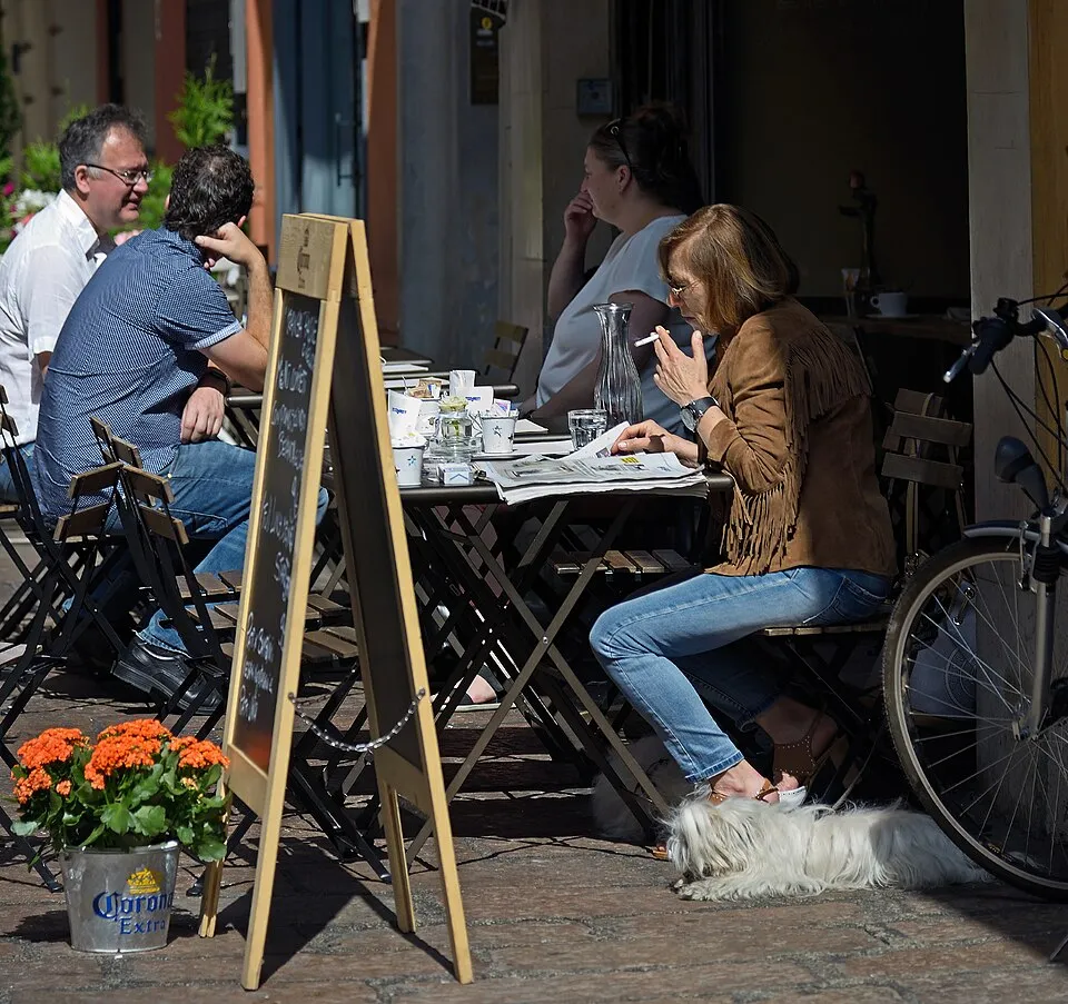 People reading a morning newspaper at a café table in Bologna, Italy