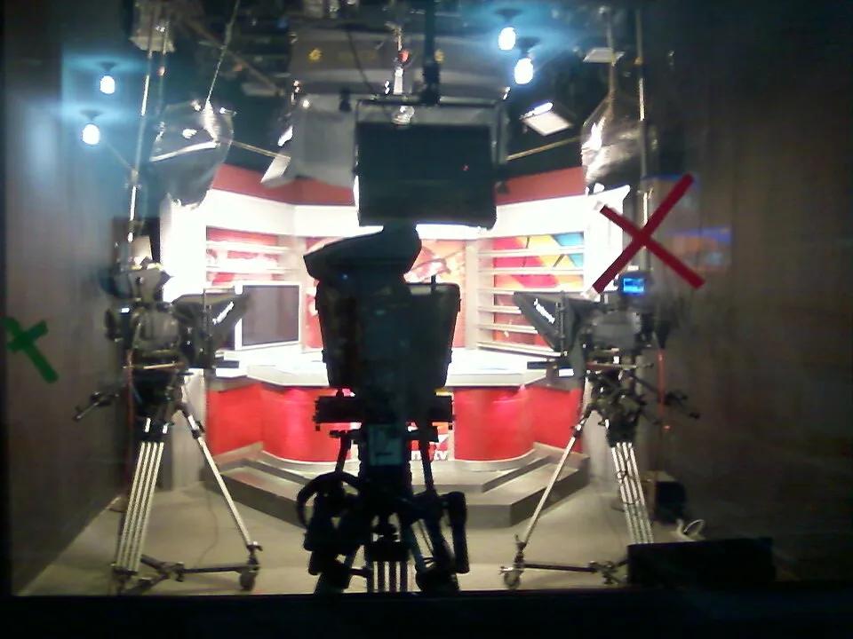 A TV news studio with cameras and bright red set lights