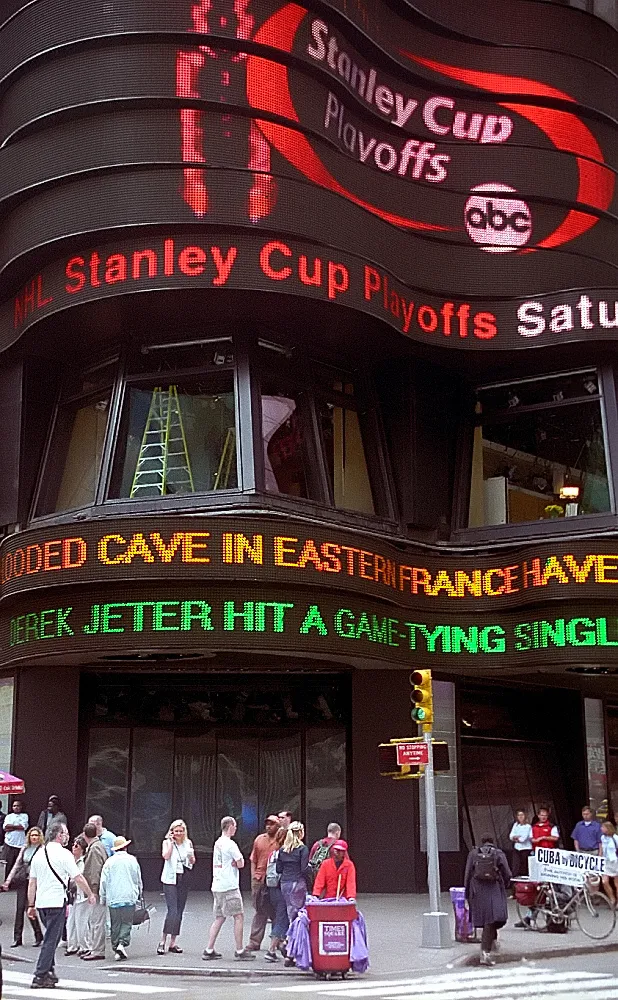 A glowing news ticker wrapping around a building in Times Square, New York