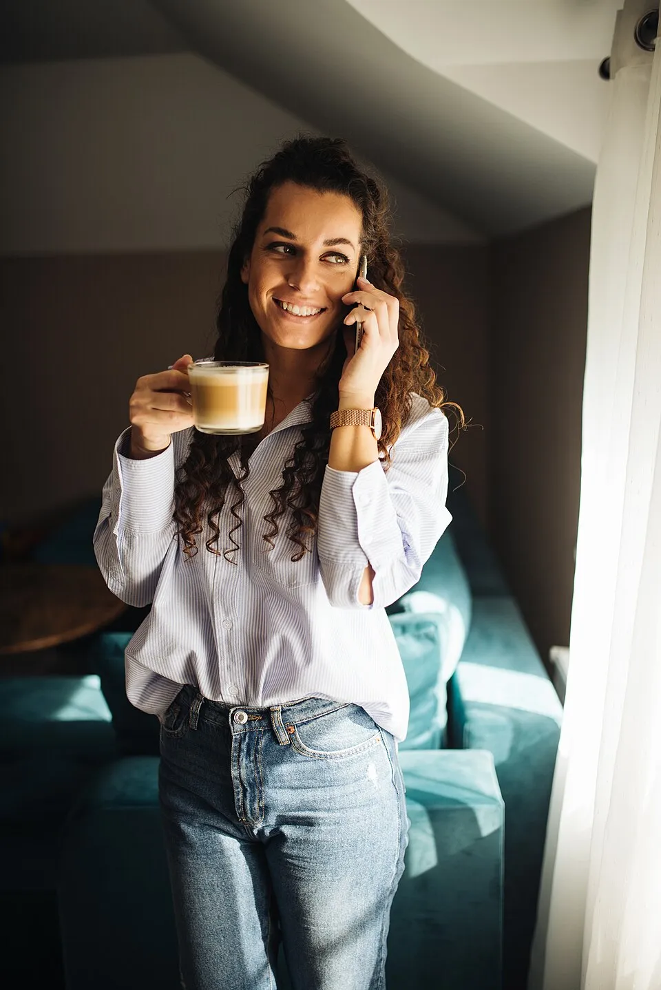 A woman chatting on her phone in a sunny room