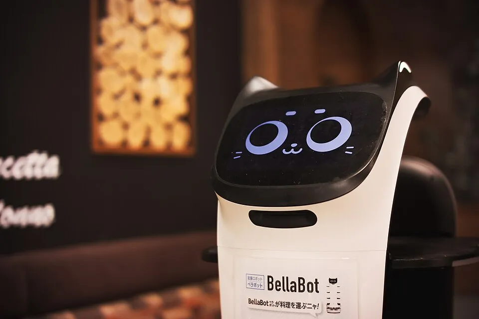 A BellaBot serving robot with a cat face on its screen in a restaurant