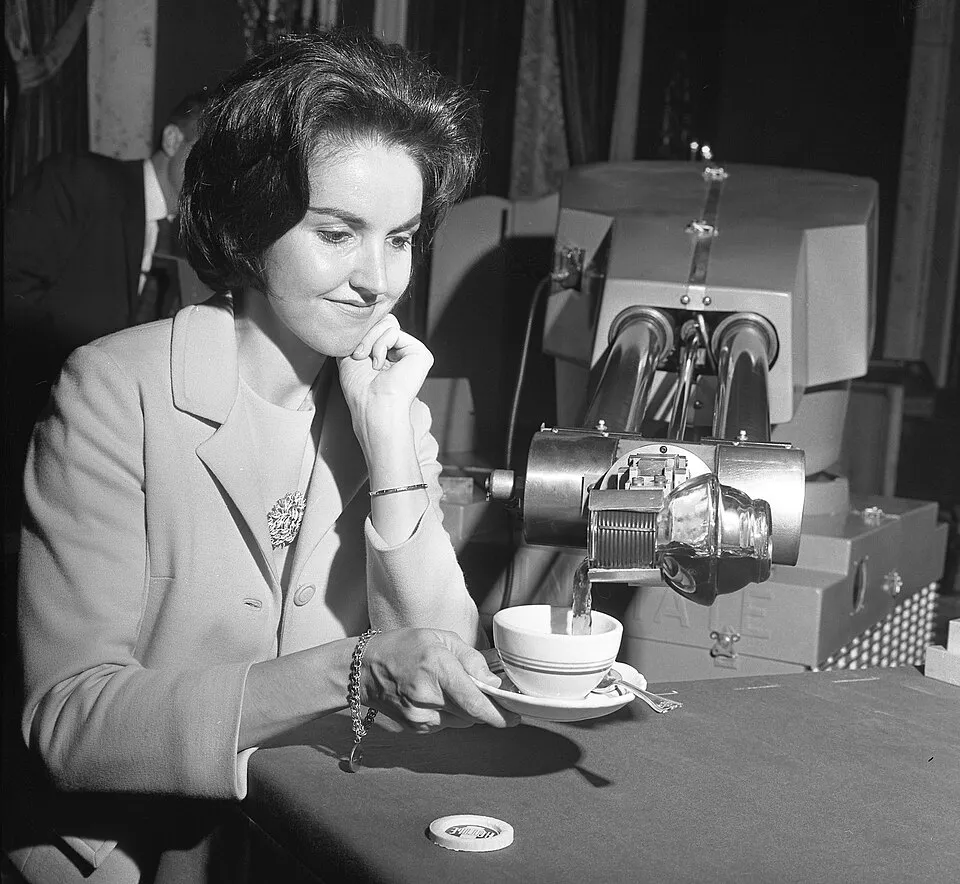 A Unimate robot arm pouring a cup of coffee for a woman at a 1967 demonstration